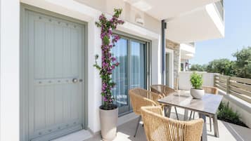 A balcony with wicker furniture and a potted plant.