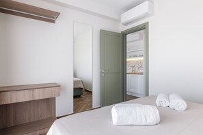 A hotel room with a bed, a bedside table, a wardrobe, and an air conditioning unit.