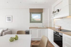 Una cocina moderna con armarios blancos, encimera de madera, horno integrado y ventana con vistas.
