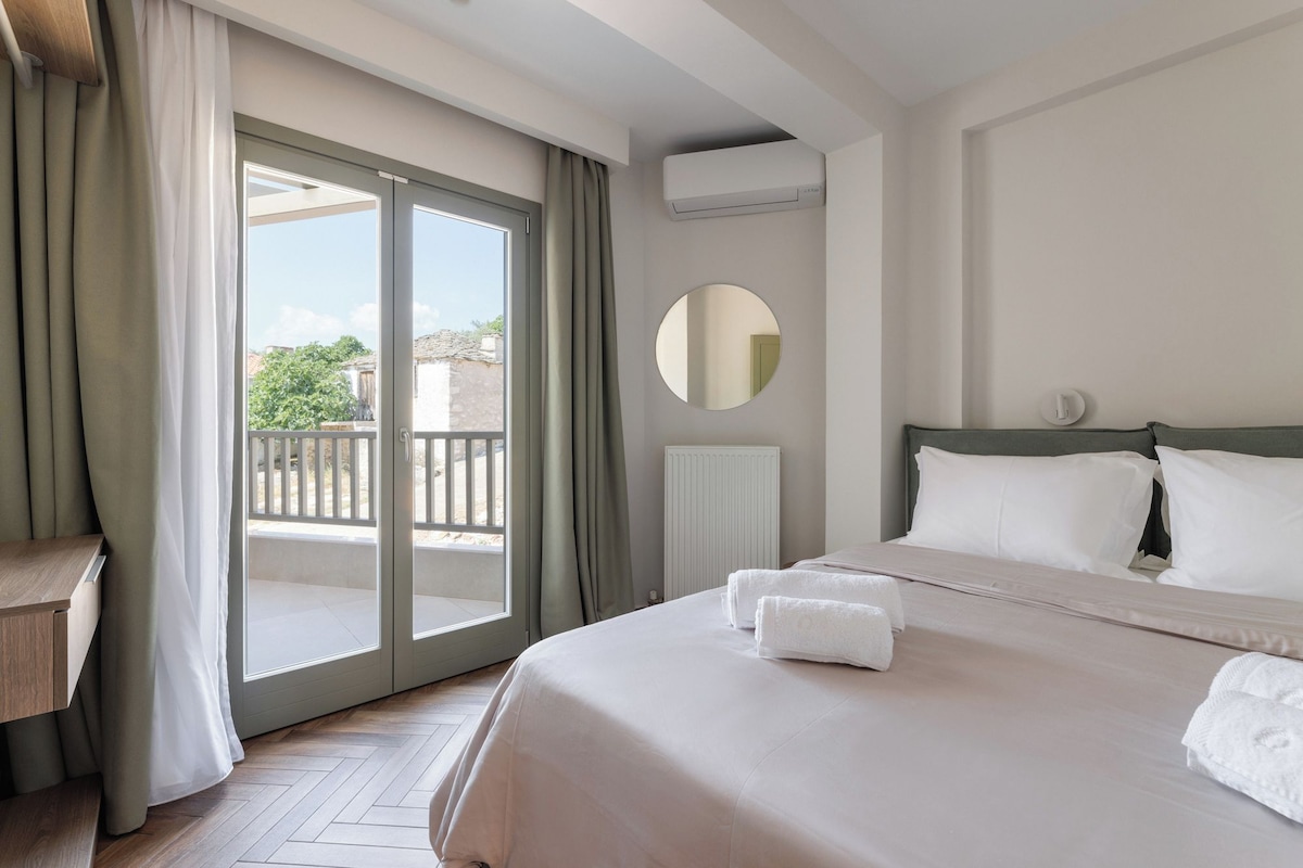 Quarto de hotel com cama, espelho redondo, radiador e vista para o exterior.