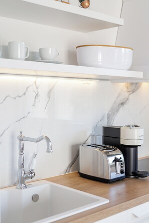 A modern kitchen with a white sink, stainless steel toaster, and a coffee maker.