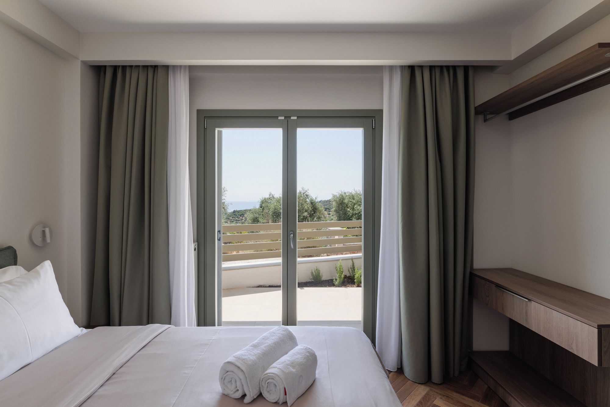 Ein Hotelzimmer mit einem Bett, einer Bank und Blick durch eine Schiebetür.