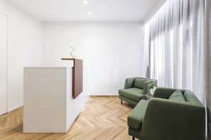 A modern living room with a white cabinet, a green sofa, and a wooden floor.