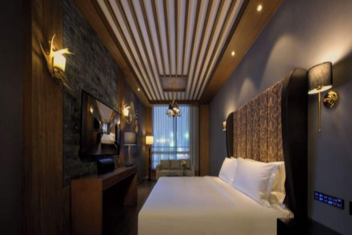 A modern hotel room with a large bed, a TV, a desk, and a city view.