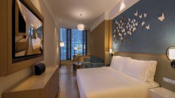 A hotel room with a large bed, a desk, a chair, a mirror, and a wall with butterfly decorations.