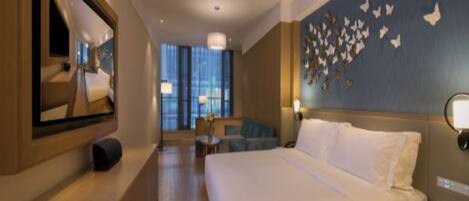 Habitación de hotel con una cama grande, un escritorio, una silla, un espejo y una pared decorada con mariposas.