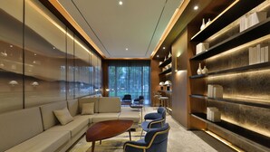Um interior moderno com um sofá, cadeiras, uma mesa de centro e estantes com objetos decorativos.