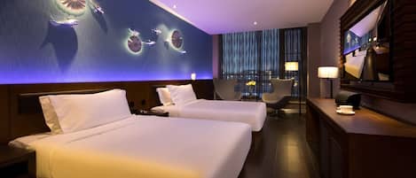 A hotel room with two beds, a desk, a chair, a large mirror, and a wall with circular light fixtures.