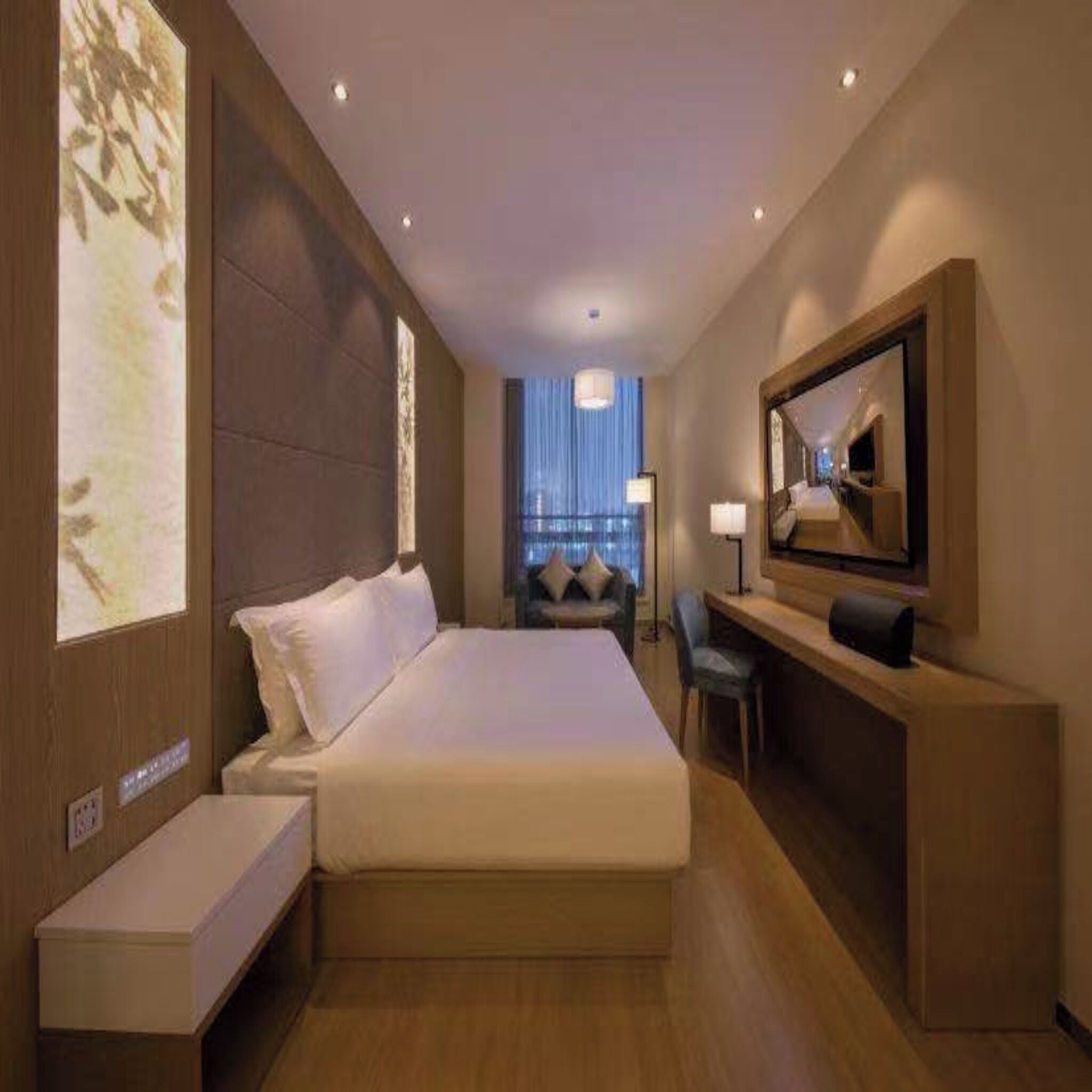 A hotel room with a large bed, a desk, a chair, a TV, and a large window with curtains.