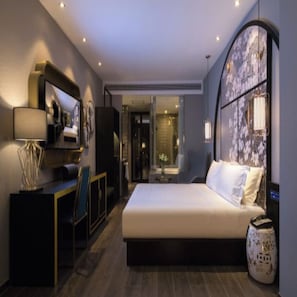 Een moderne hotelkamer met een bed, bureau en een gebogen muur met een decoratief patroon.