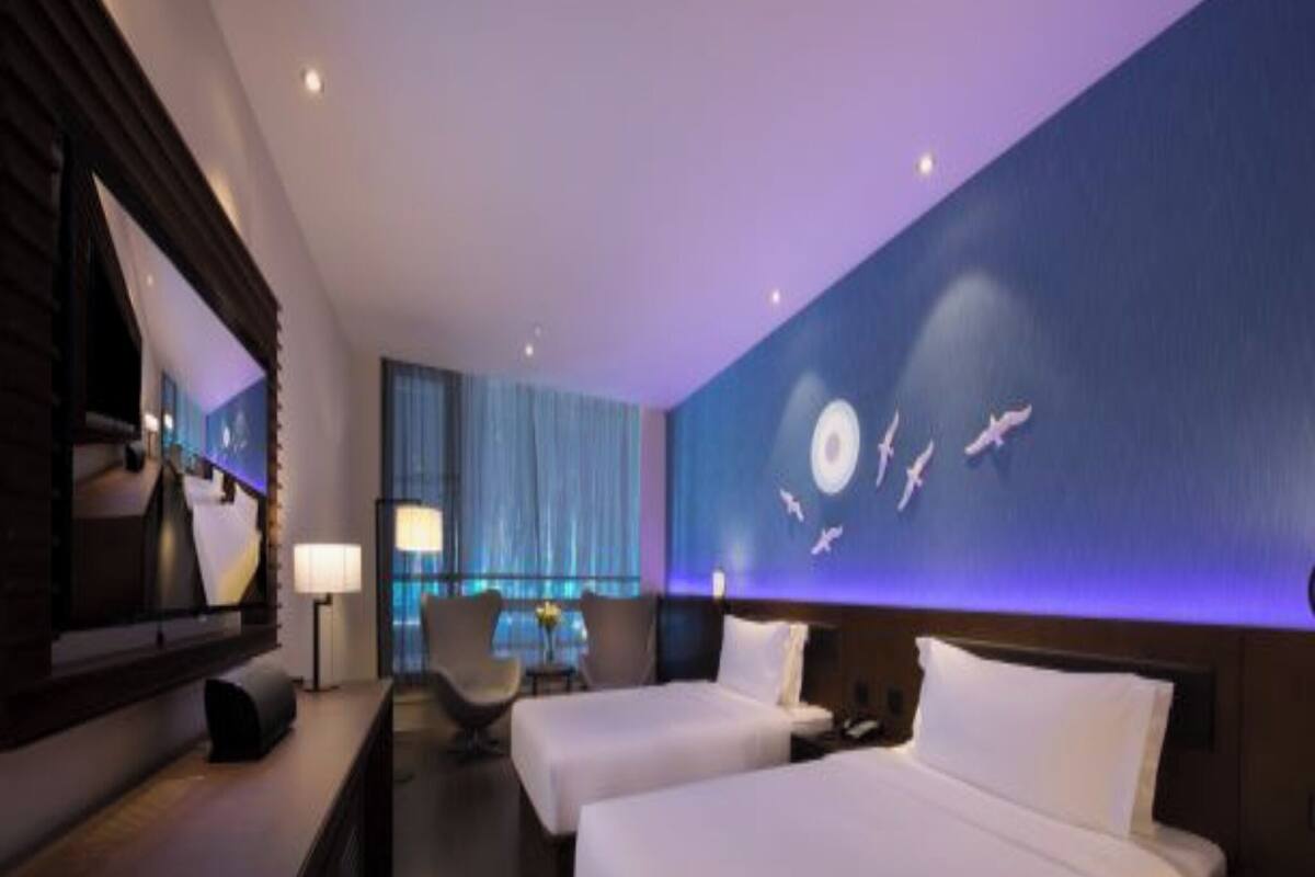 A hotel room with two beds, a desk, a chair, and a large wall mural.