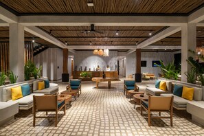 Een ruime lobby met een centraal gelegen zitgedeelte, een bar en een receptiebalie.
