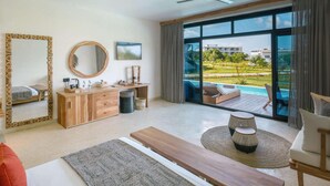 Ein modernes Hotelzimmer mit großem Fenster, einem Holztisch, einem Bett und einer Sitzecke mit Blick auf einen Pool und Grünflächen.