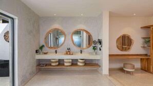 Ein Badezimmer mit zwei runden Spiegeln, einem Holztischchen und einem kleinen Hocker.
