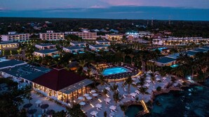 Eine Vogelperspektive eines Resorts mit mehreren Gebäuden, einem Swimmingpool und einem Strandbereich mit Sonnenschirmen.