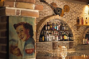 Zona de bar con pared de ladrillo, una guitarra y varias botellas de licor.