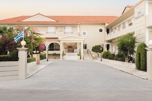 A hotel with a red-tiled roof, a central entrance with steps, and a flagpole with a flag. - Kalamaki Beach Zakynthos (Zakynthos)