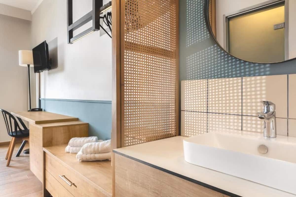 A modern bathroom with a large sink, a mirror, and a wooden partition.