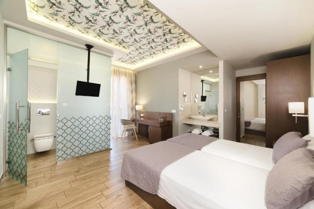 Ein Hotelzimmer mit Bett, Schreibtisch, Spiegel, Fernseher und Bad.