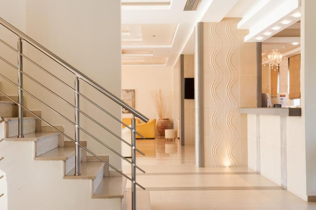 A modern hotel lobby with a staircase, a reception desk, and a wavy wall design.