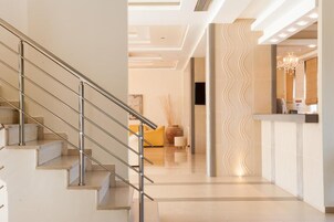 Un moderno vestíbulo de hotel con una escalera, un mostrador de recepción y un diseño de pared ondulado.