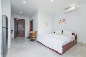 Un dormitorio con cama, escritorio, silla, puerta y aire acondicionado.