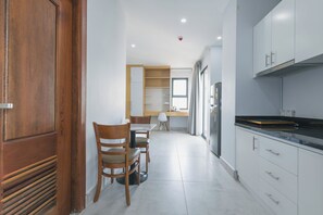 Eine moderne Küche mit weißen Schränken, einer schwarzen Arbeitsplatte und einem Essbereich mit Holztischen und einem Tisch.