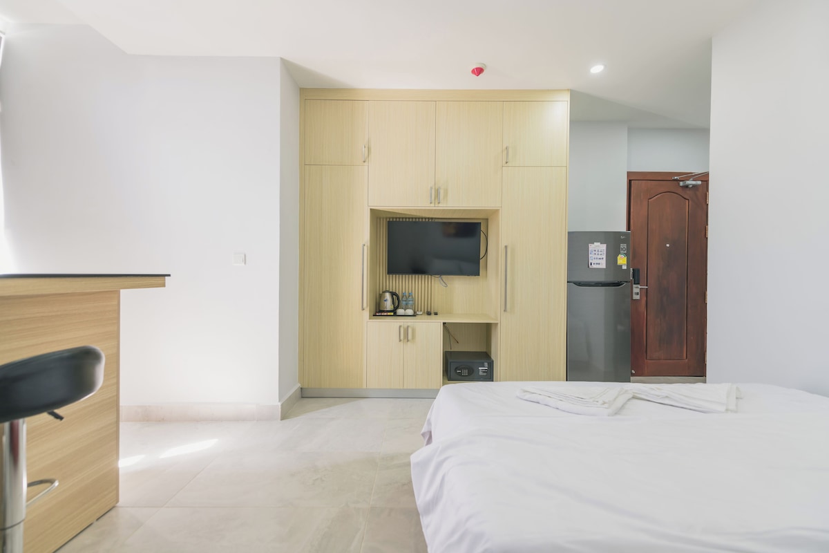 Una habitación de hotel con cama, televisión, minibar y armario de madera.