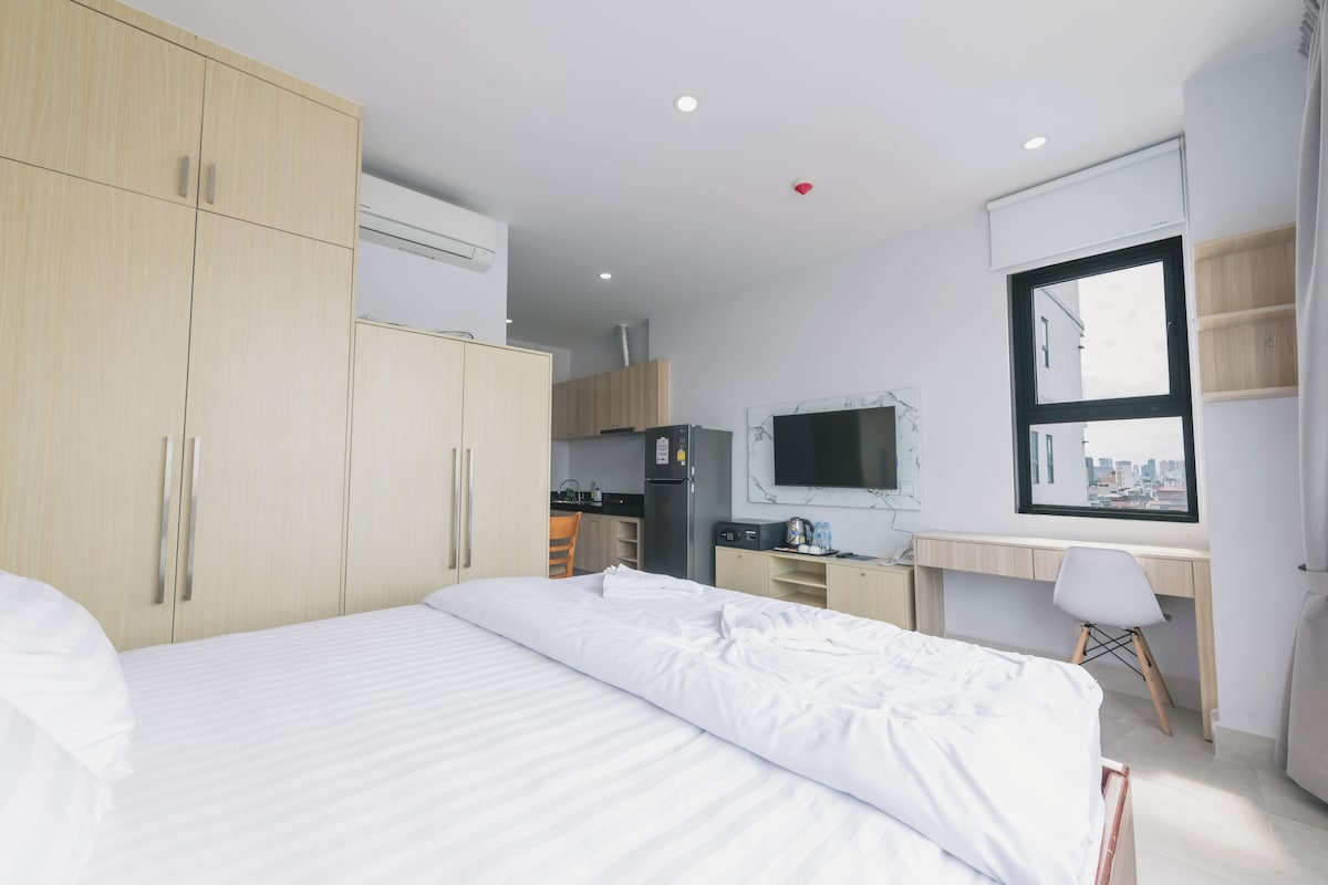 Una habitación de hotel con una cama, un escritorio, una silla y una kitchenette.