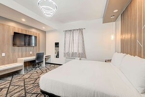 Une chambre d’hôtel équipée d’un lit, d’un bureau, d’une chaise et d’un téléviseur fixé au mur.