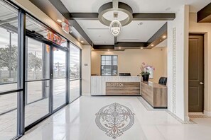 Un espace d’accueil comprenant un comptoir de réception, une grande fenêtre et un motif décoratif sur le sol.