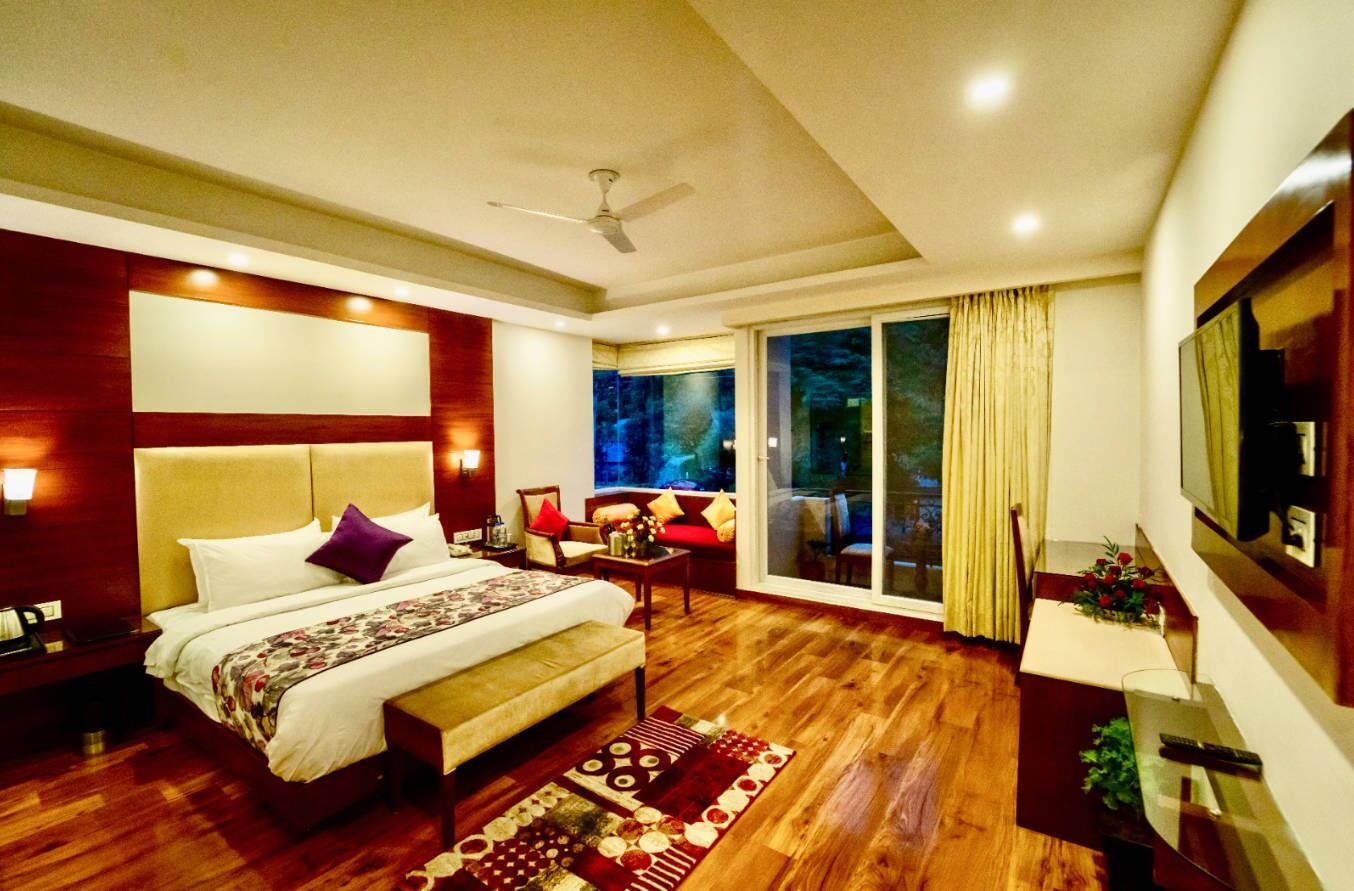 A hotel room with a bed, a desk, a chair, a TV, and a large window.