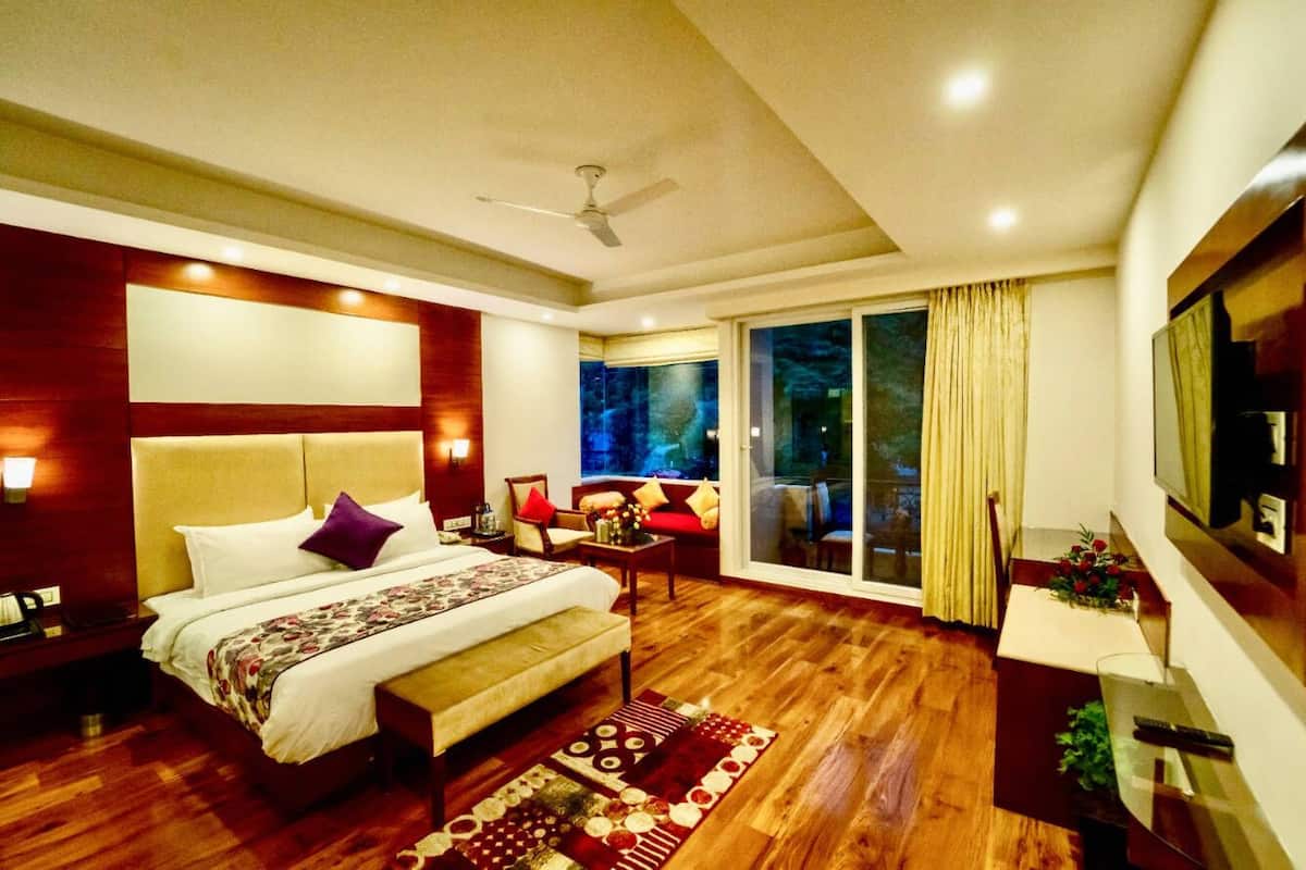 A hotel room with a bed, a desk, a chair, a TV, and a large window.