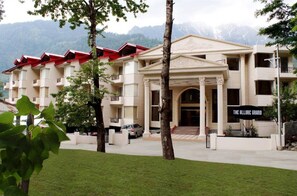 A hotel with a central entrance, multiple balconies, and a mountainous backdrop. - Allure Grand Resort (Manali)