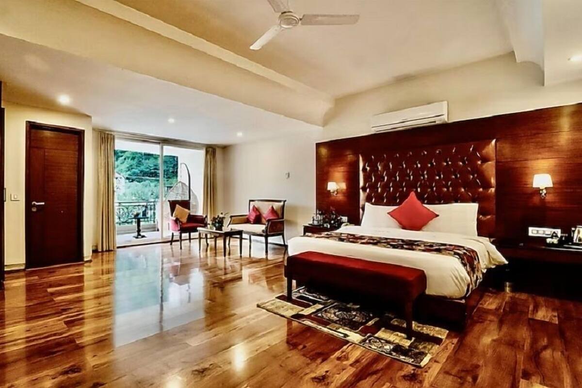 A spacious bedroom with a large bed, a wooden floor, a ceiling fan, and a view of the outdoors.