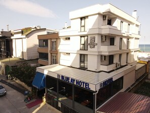 Um hotel de vários andares com telhado plano, grandes janelas e uma placa indicando ser o Blue Ay Hotel.