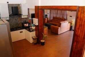 Un espacio habitable compacto con kitchenette, un sofá, zona de comedor y una planta en maceta.