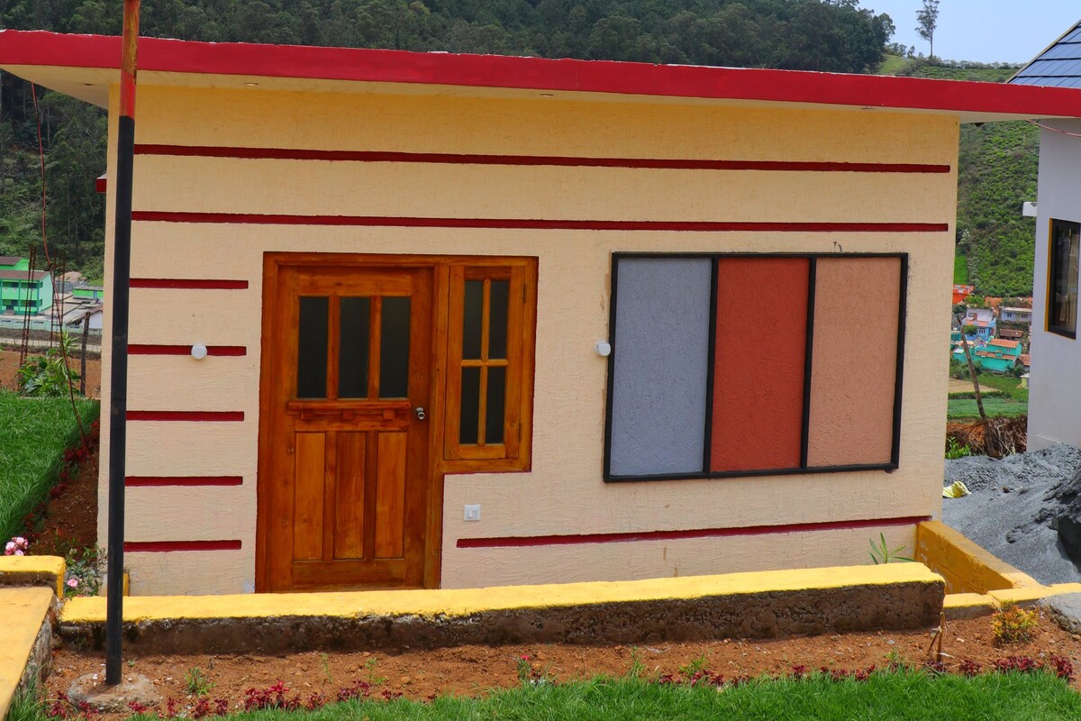A small building with a red roof, a wooden door, and a window with a red frame.