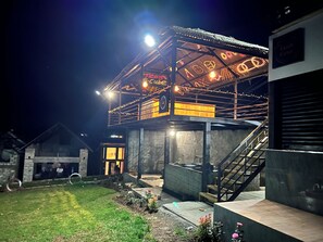 A building with a covered outdoor area, a staircase, and a sign with illuminated text. - The Frame Resorts Ooty (Coonoor)
