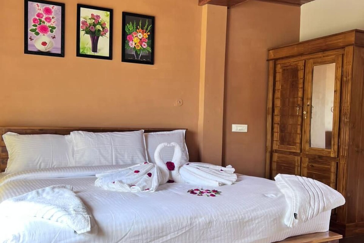 A hotel room with a large bed, wooden headboard, and a wardrobe.