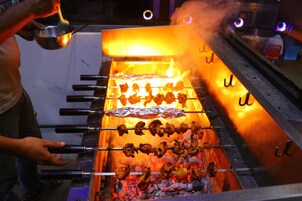 Una parrilla con brochetas de comida cocinándose sobre fuego abierto.