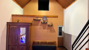 A staircase with a wooden handrail, a wooden bench, a clock, and a cabinet with a glass door.