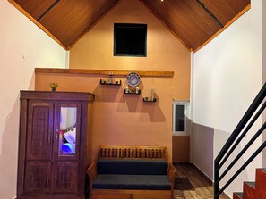 A staircase with a wooden handrail, a wooden bench, a clock, and a cabinet with a glass door. - The Frame Resorts Ooty (Coonoor)