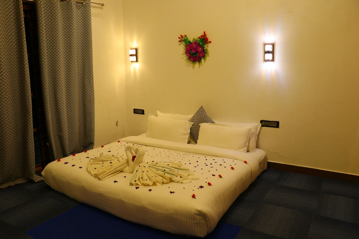 A hotel room with a neatly made bed, a wall-mounted light fixture, and a floral decoration.