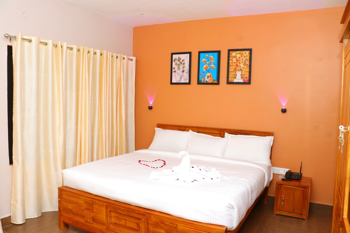 A hotel room with a bed, a nightstand, a wall-mounted lamp, and a door.