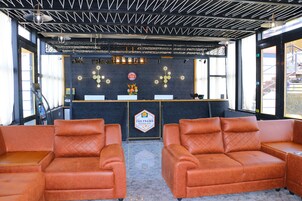 A bar area with a counter, two brown leather sofas, and a ceiling with exposed beams.