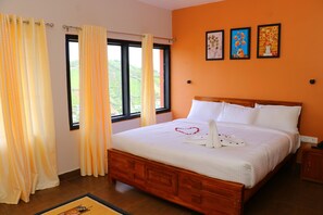 Una cama bien hecha con sábanas blancas y una decoración con forma de corazón, una ventana con cortinas y tres cuadros en la pared.