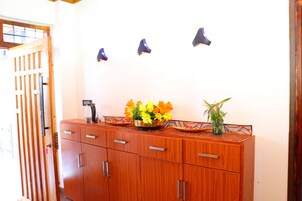 A wooden cabinet with drawers, a coffee maker, and a vase with flowers.