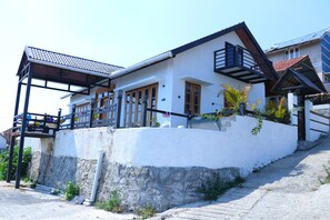 A two-story house with a balcony, a stone base, and a tiled roof. - The Frame Resorts Ooty (Coonoor)