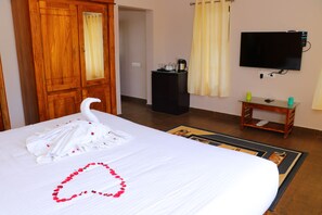 A hotel room with a bed, a wooden wardrobe, a television, and a small table with a remote control. - The Frame Resorts Ooty (Coonoor)